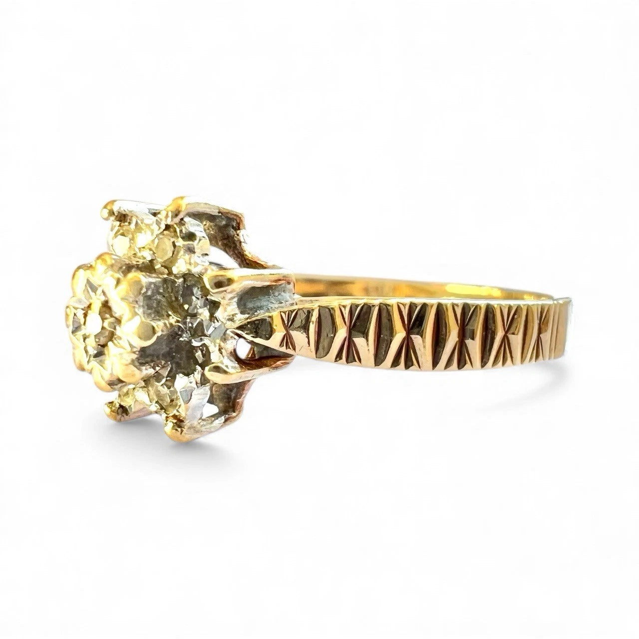 Gold diamond cluster ring with a textured gold band on a white background, close up side view. 