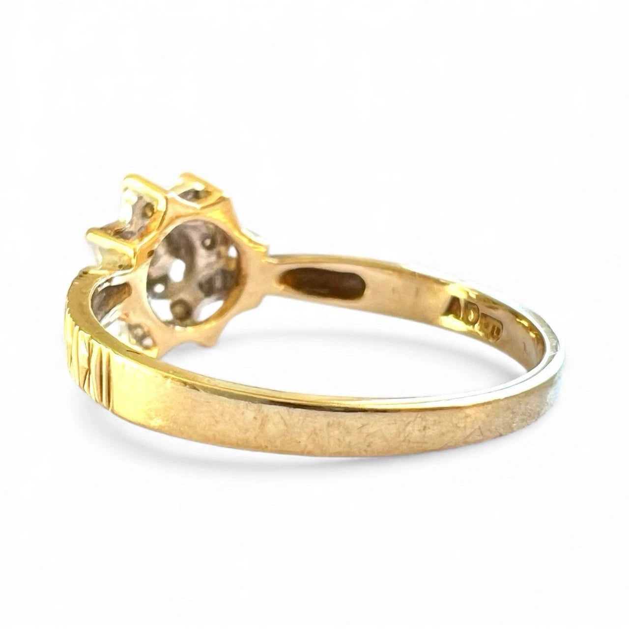Gold cluster ring with a diamond on a white background, close up view of gold band 