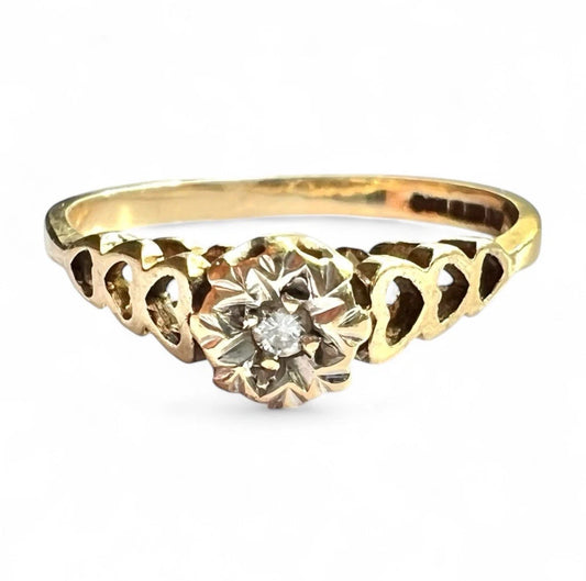 Gold ring with a diamond with hear detailed band on a white background close up front view 