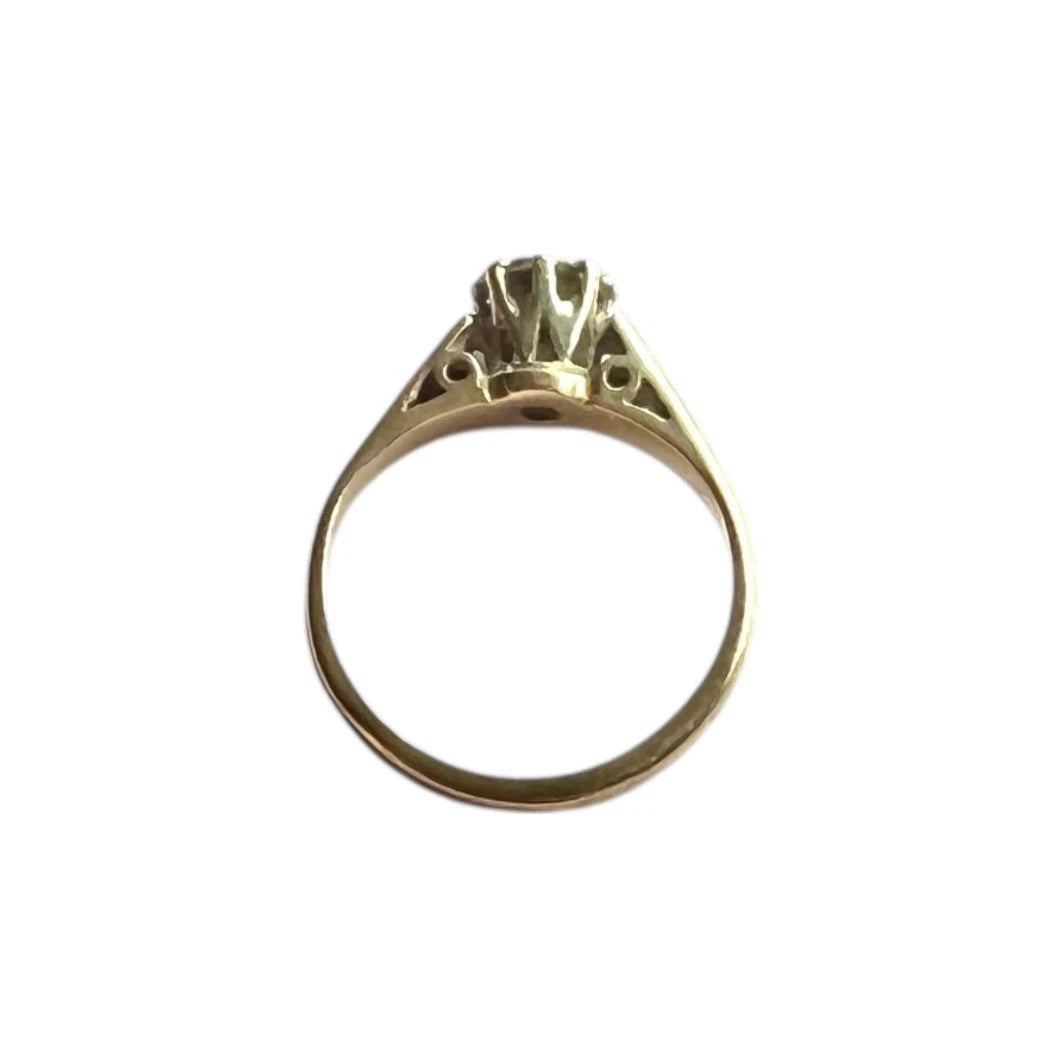 Gold ring with a diamond on a white background, top down view. 