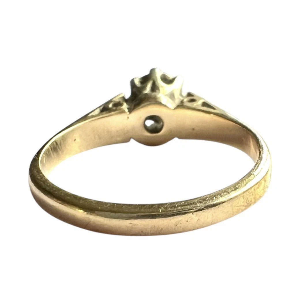 Gold ring with a central diamond on a white background, close up rear view of setting and band 