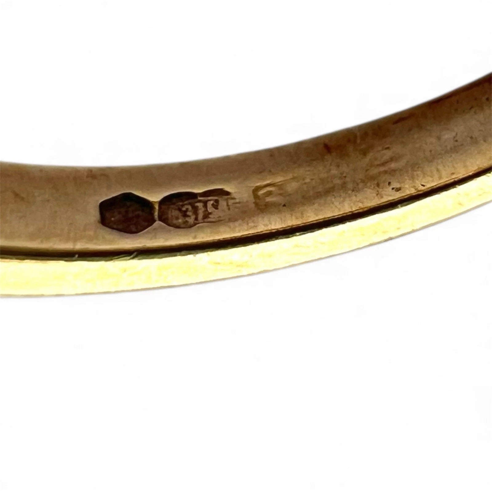 Close-up of a gold ring with visible hallmarking on a white background