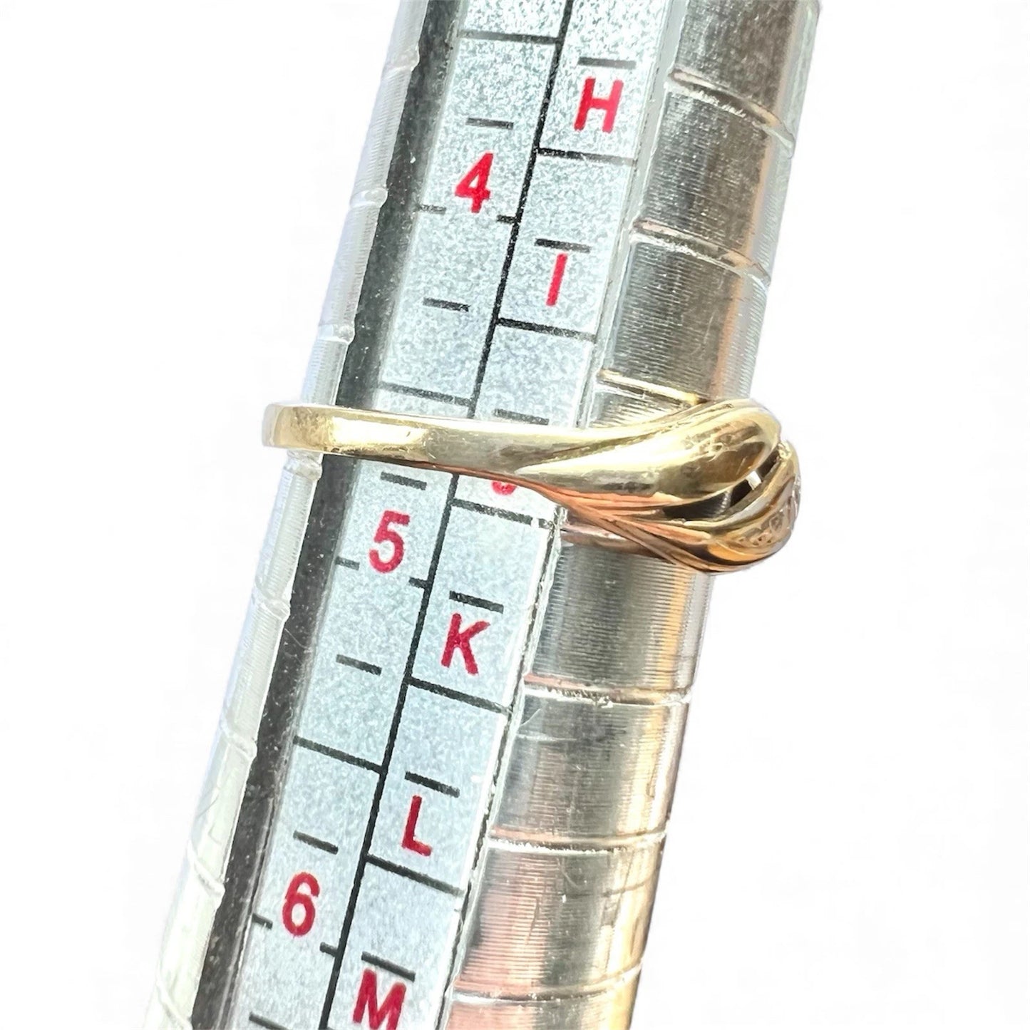 Gold ring being measured against a ring sizer on a white background
