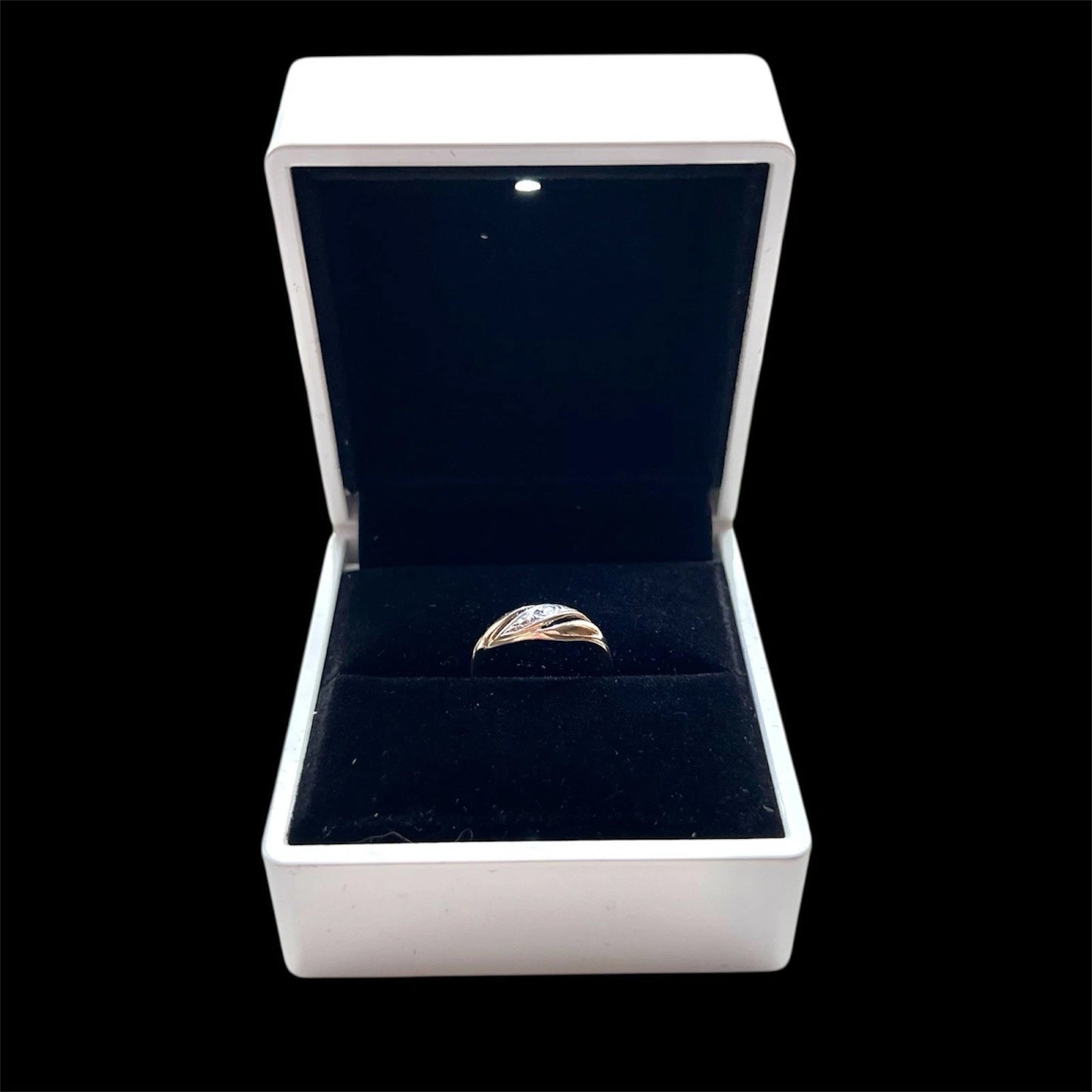 Gold diamond twist ring in an open jewellery box with a black interior
