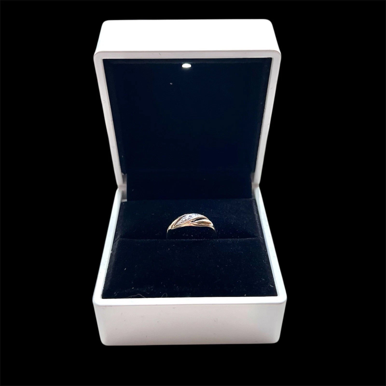Gold diamond twist ring in an open jewellery box with a black interior