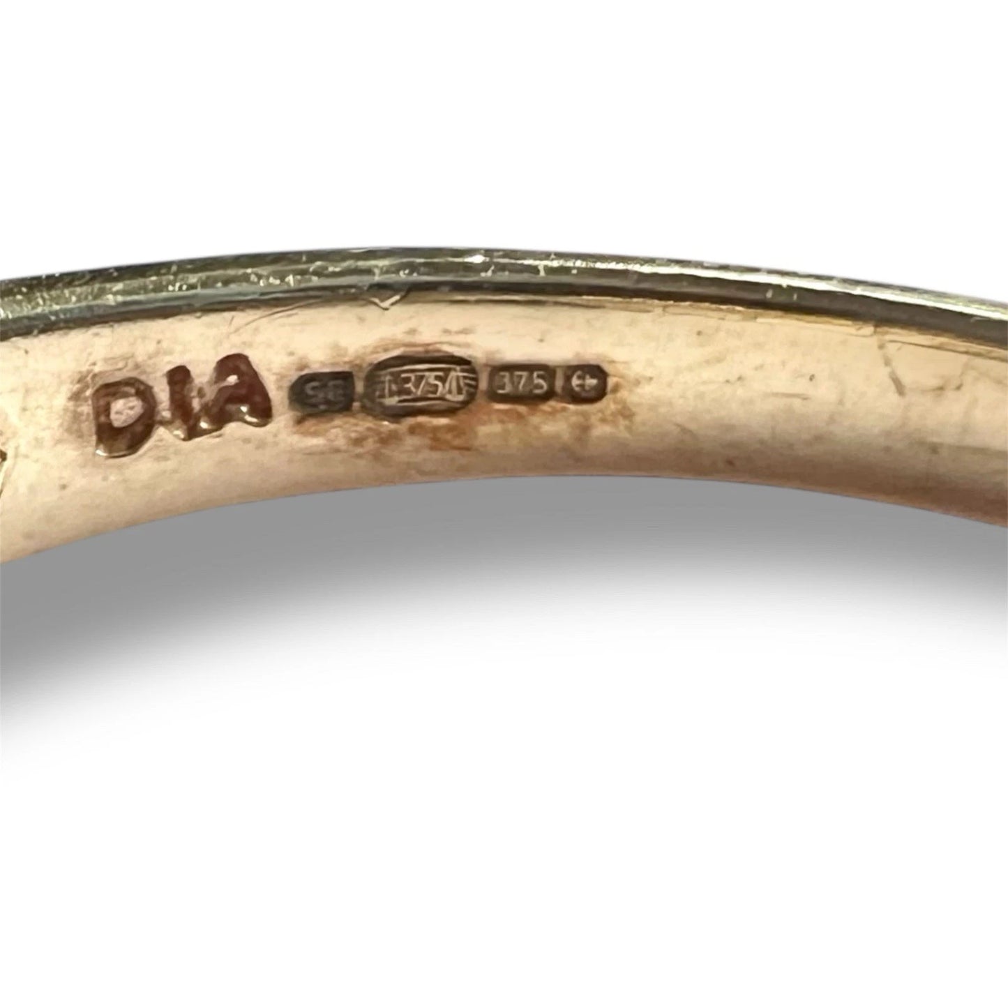 Close-up of a gold ring with 'DIA' and '375' hallmark on a white background