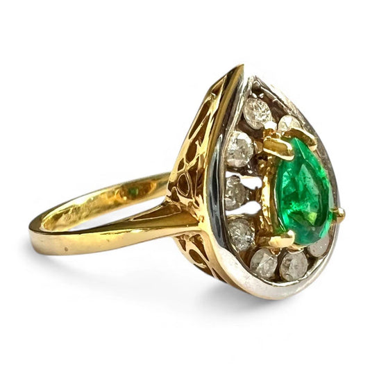 Gold ring with a green emerald gemstone and diamond halo on a white background