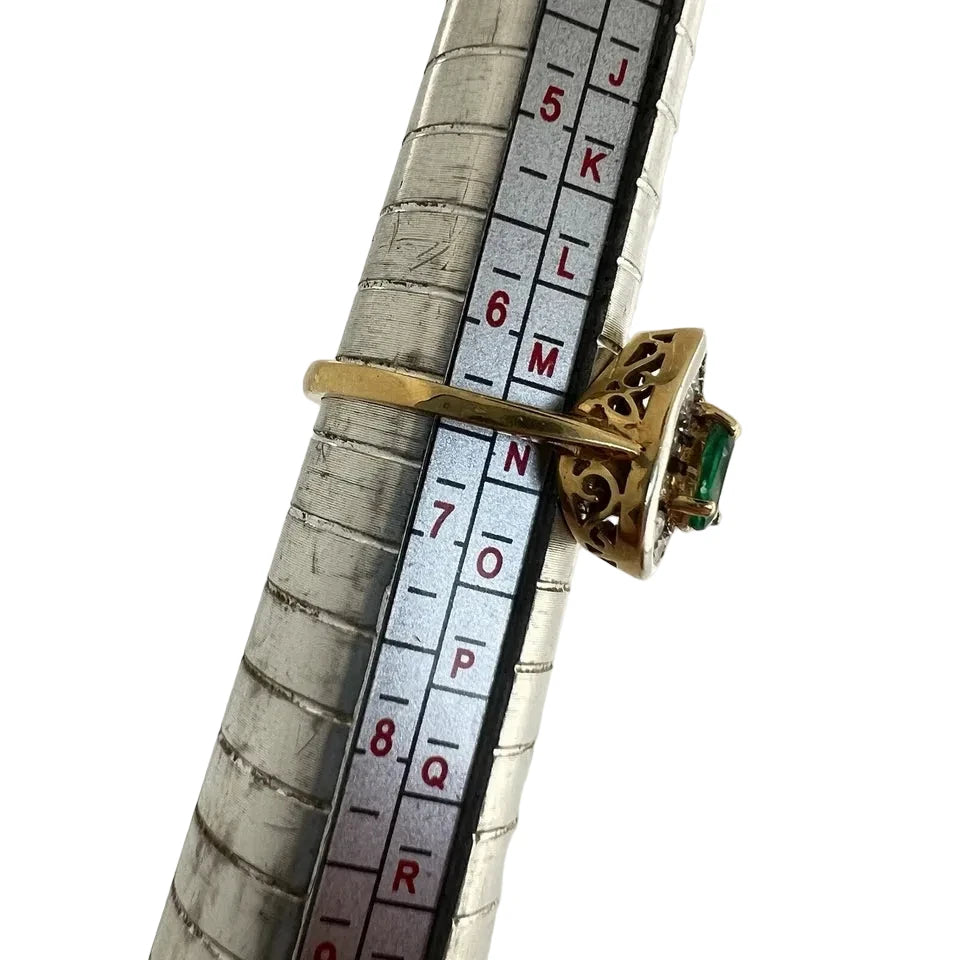 Gold ring with a green emerald gemstone on a ruler for size reference