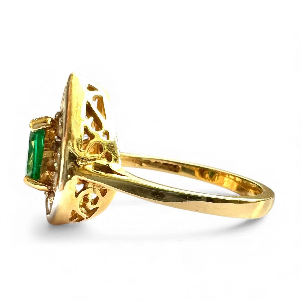 Gold ring with green emerald gemstone on a white background