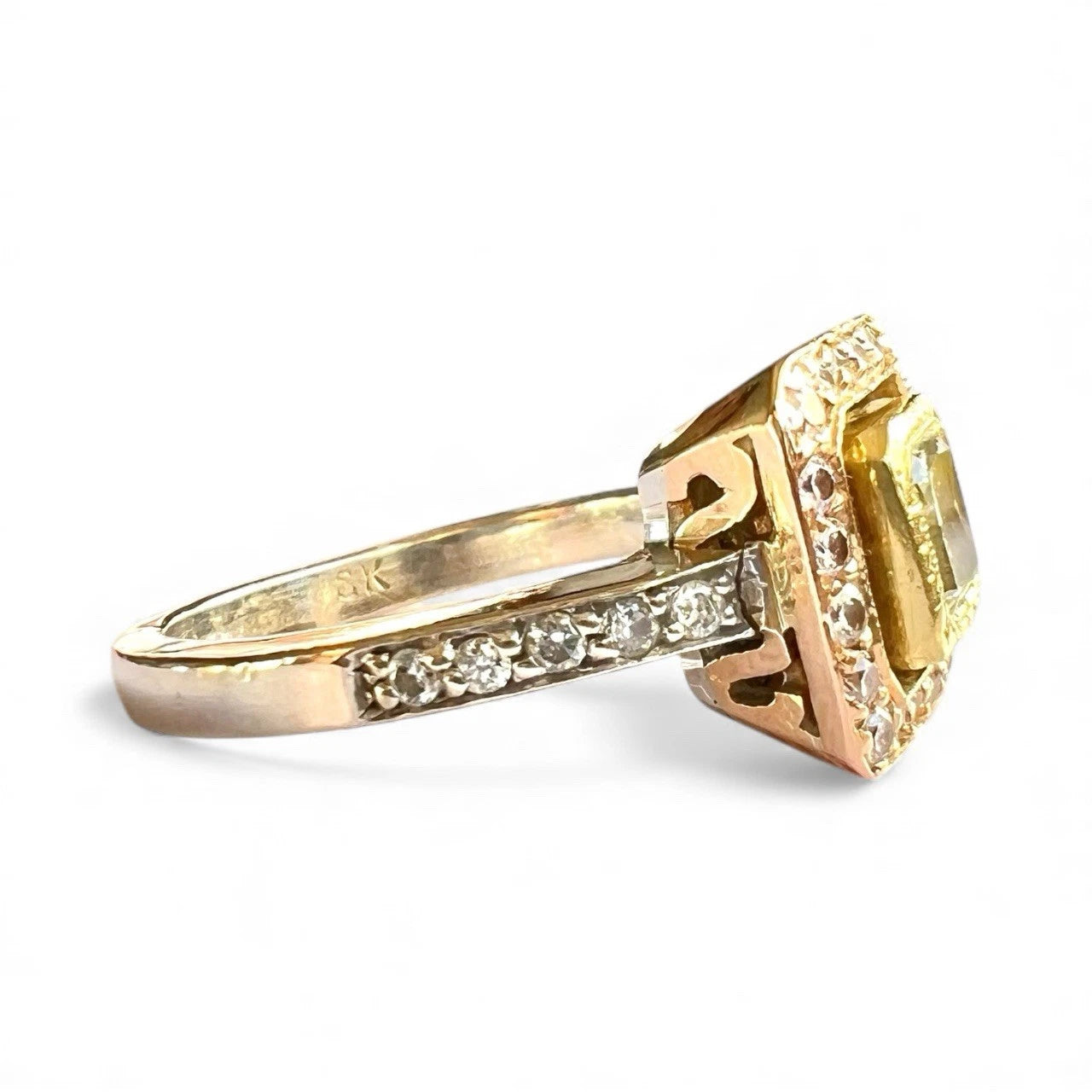 Gold ring with a large yellow diamond and smaller diamonds on a white background
