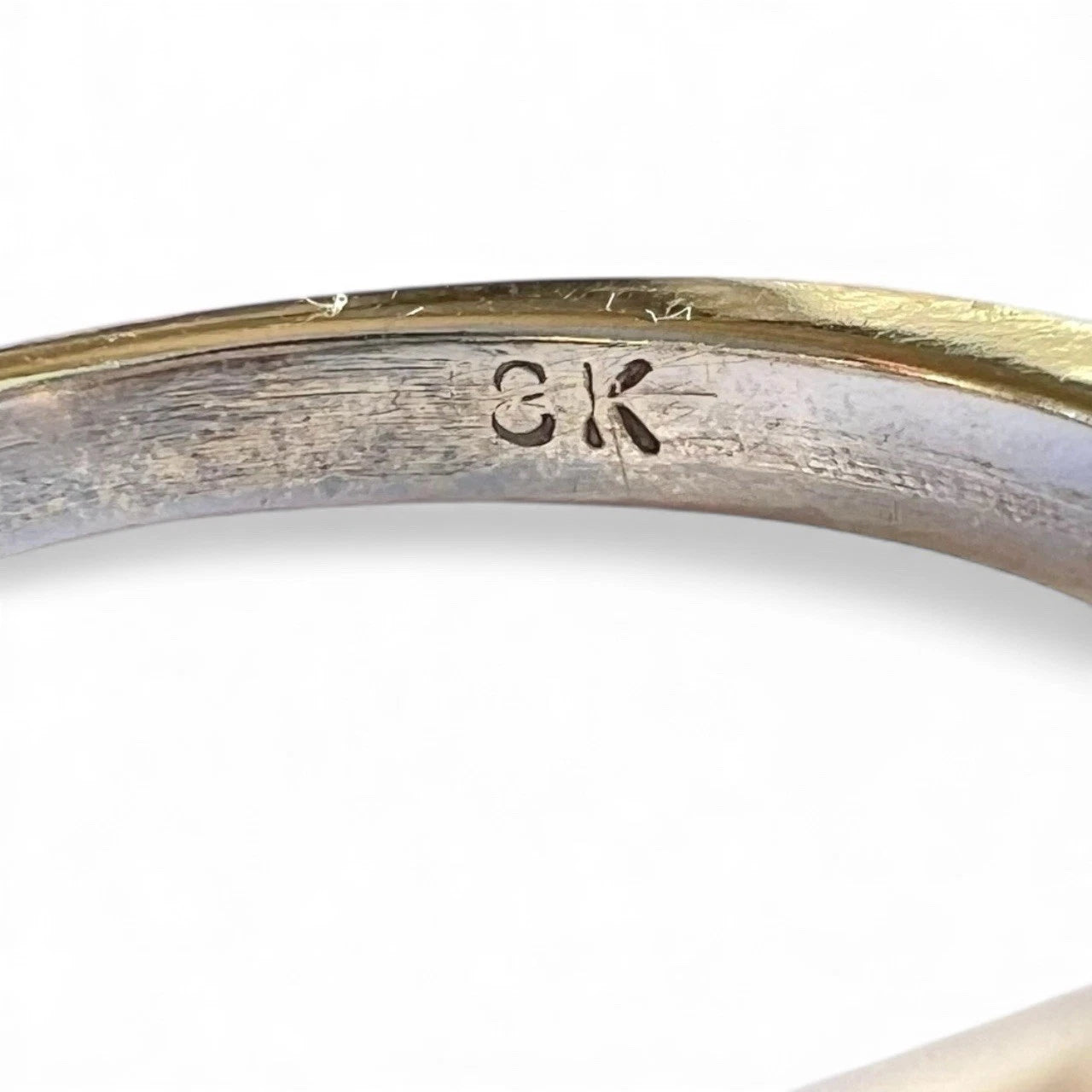 Close-up of a gold ring with indistinct '18K' engraving on a white background