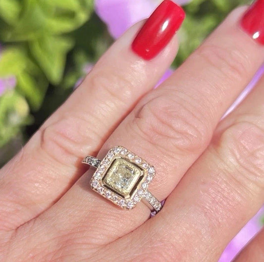 Gold ring with a diamond on a hand with red nail polish against a blurred floral background