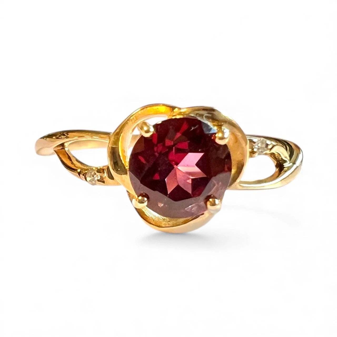 Gold ring with a red garnet gemstone on a white background. Close up front view 