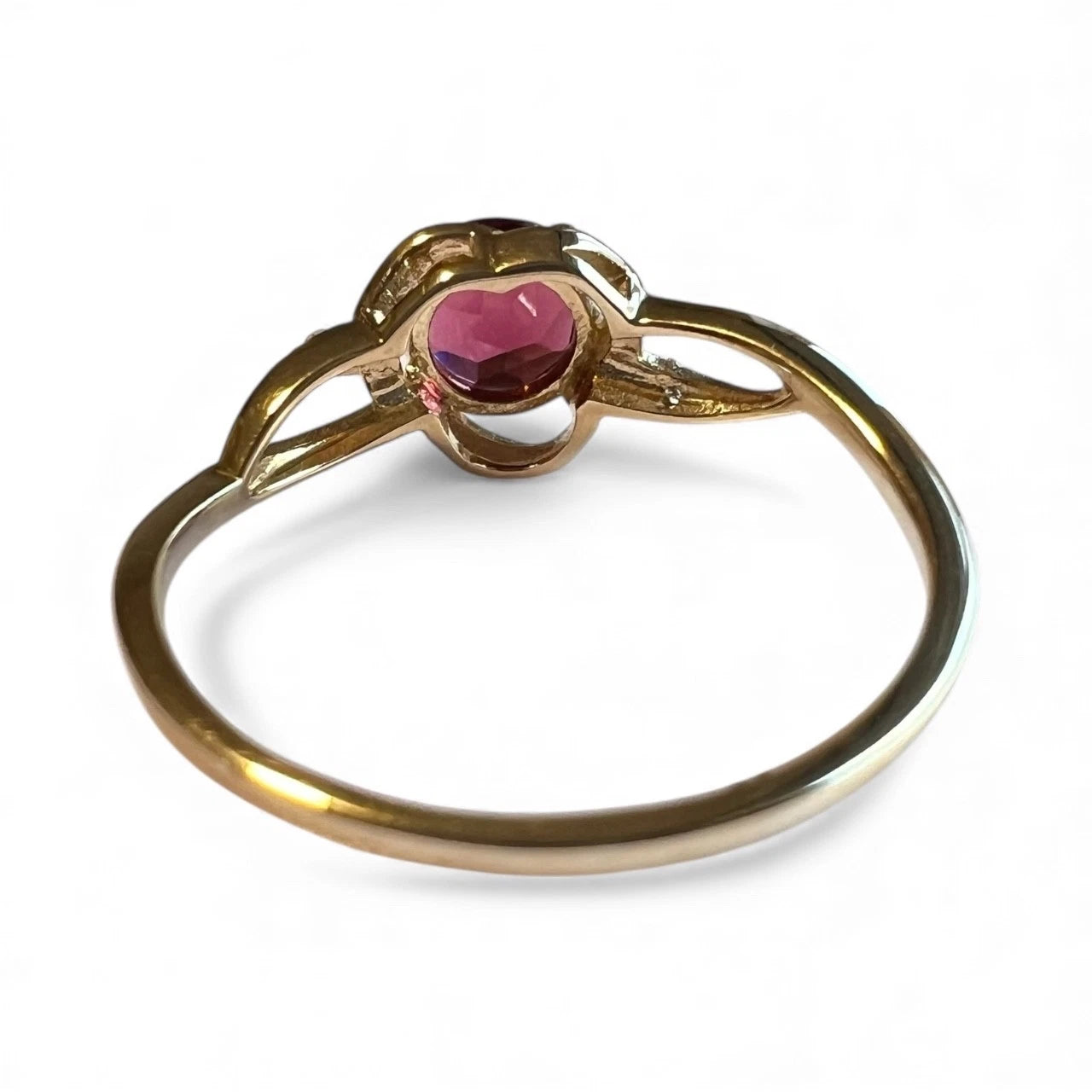 Gold ring with a red gemstone on a white background. Close rear view of setting and gold band 