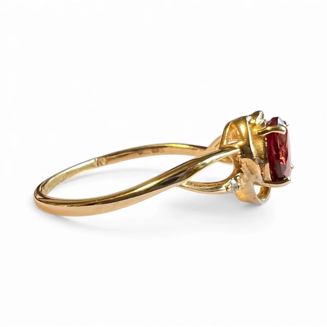 Gold ring with a red gemstone on a white background side view close up