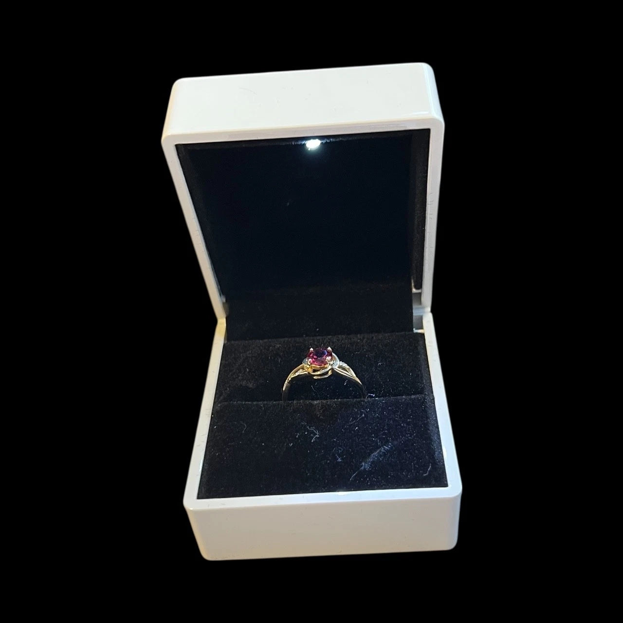 Garnet solitaire ring in an open jewellery box on a black background