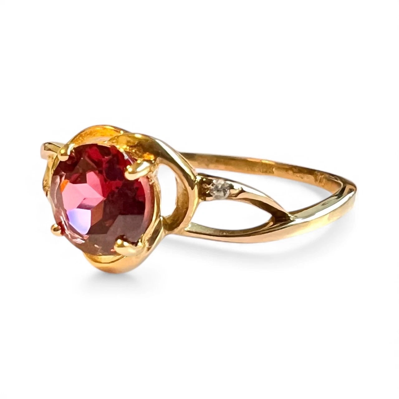 Gold ring with a red garnet Gemstones diamond assents on a white background. Side view close up