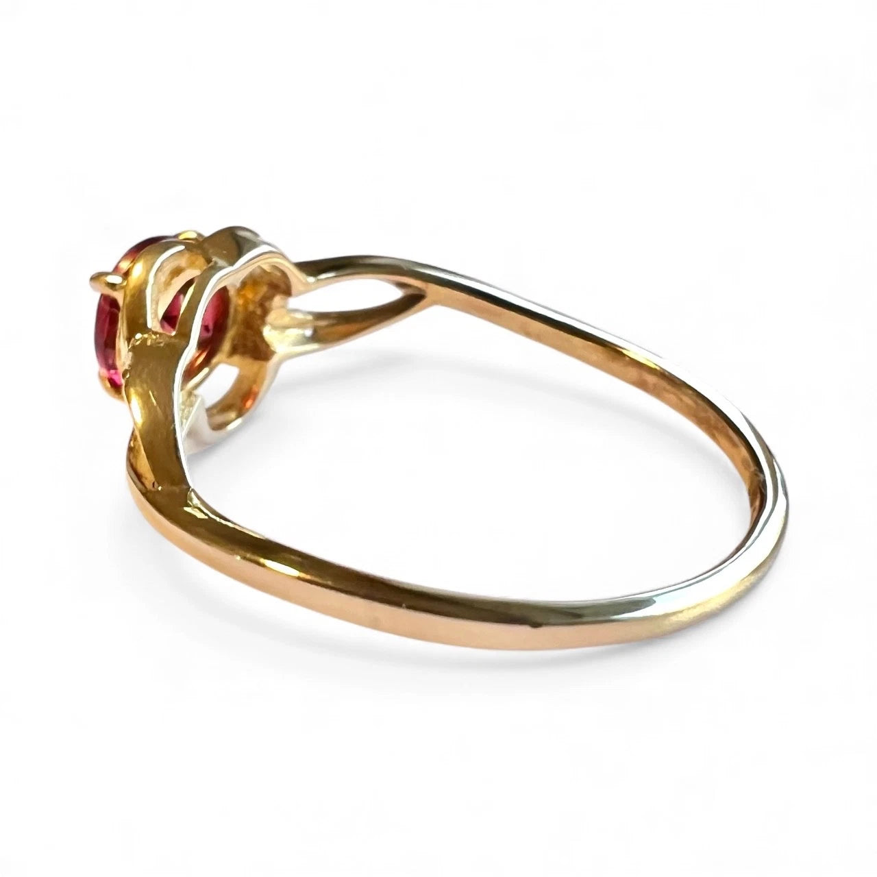 Gold ring with red garnet gemstones on a white background