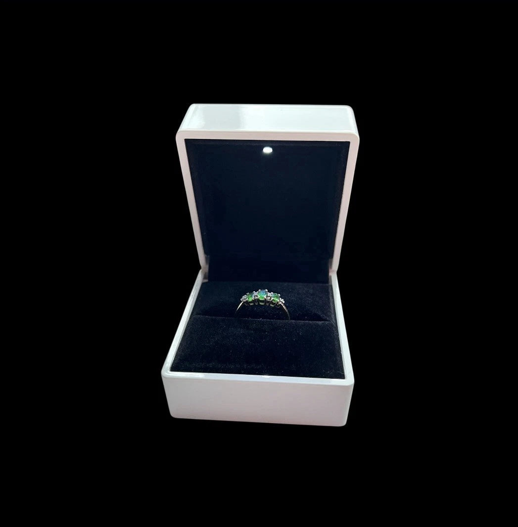 Gold ring with Green diopside and diamond in a white jewellery box on a black background 