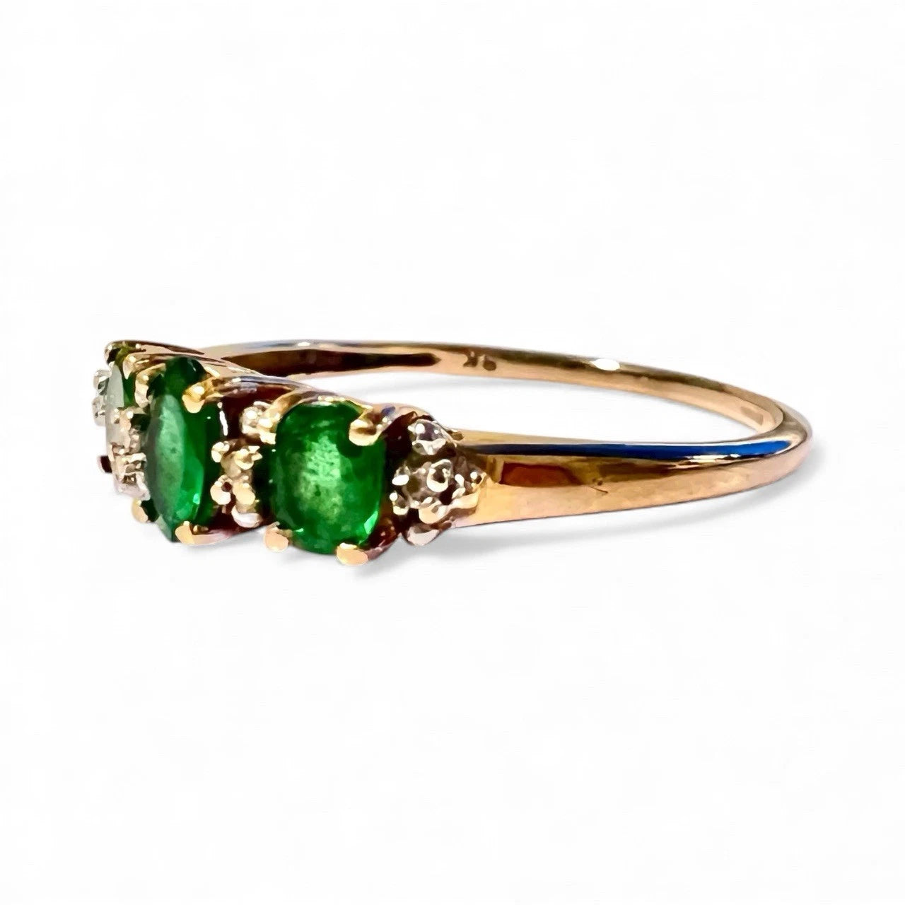 Three stone gold ring with Green diopside and diamond side view close up on a white background 