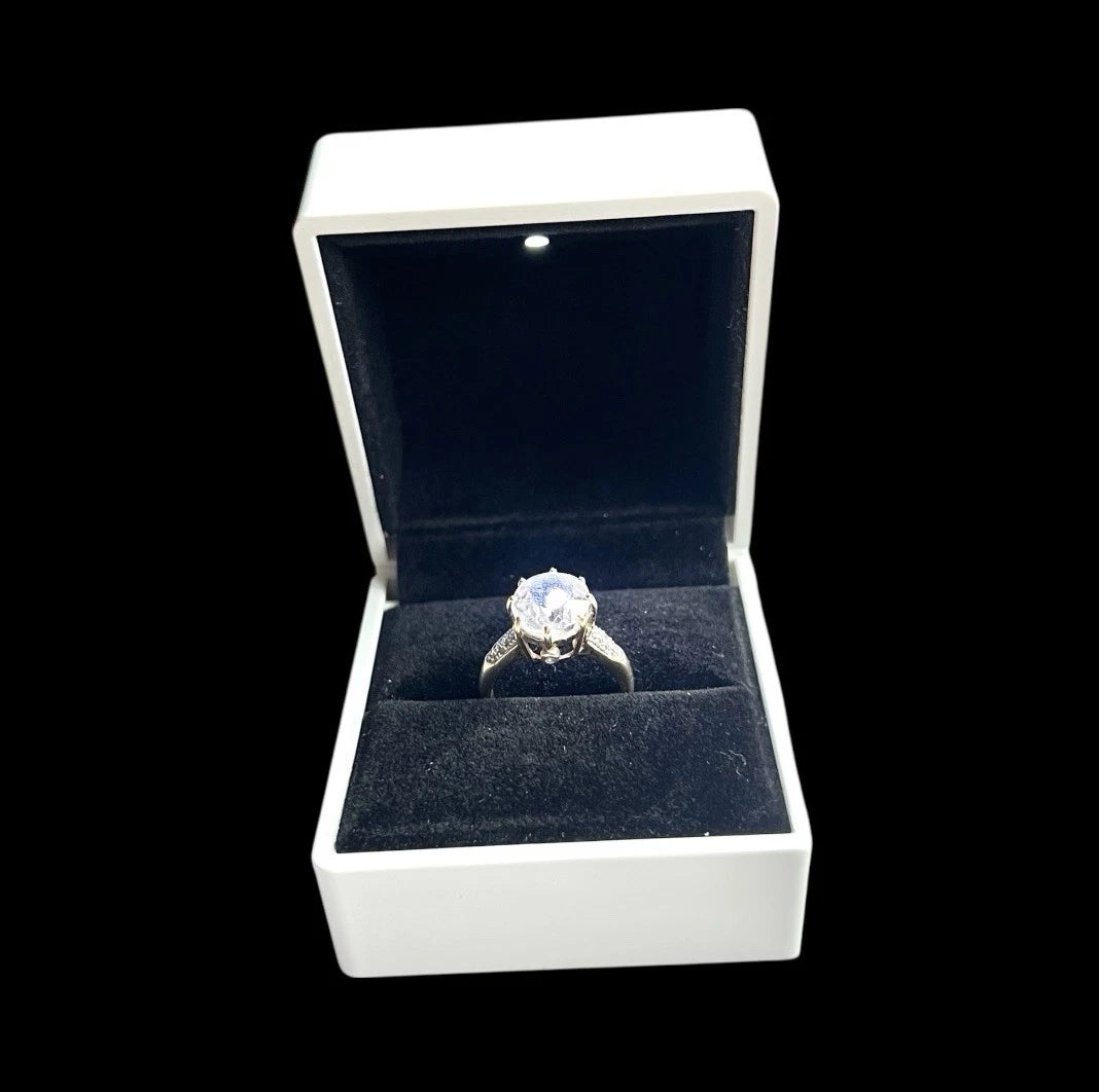 Large quartz and diamond ring in a white box with a black interior on a black background