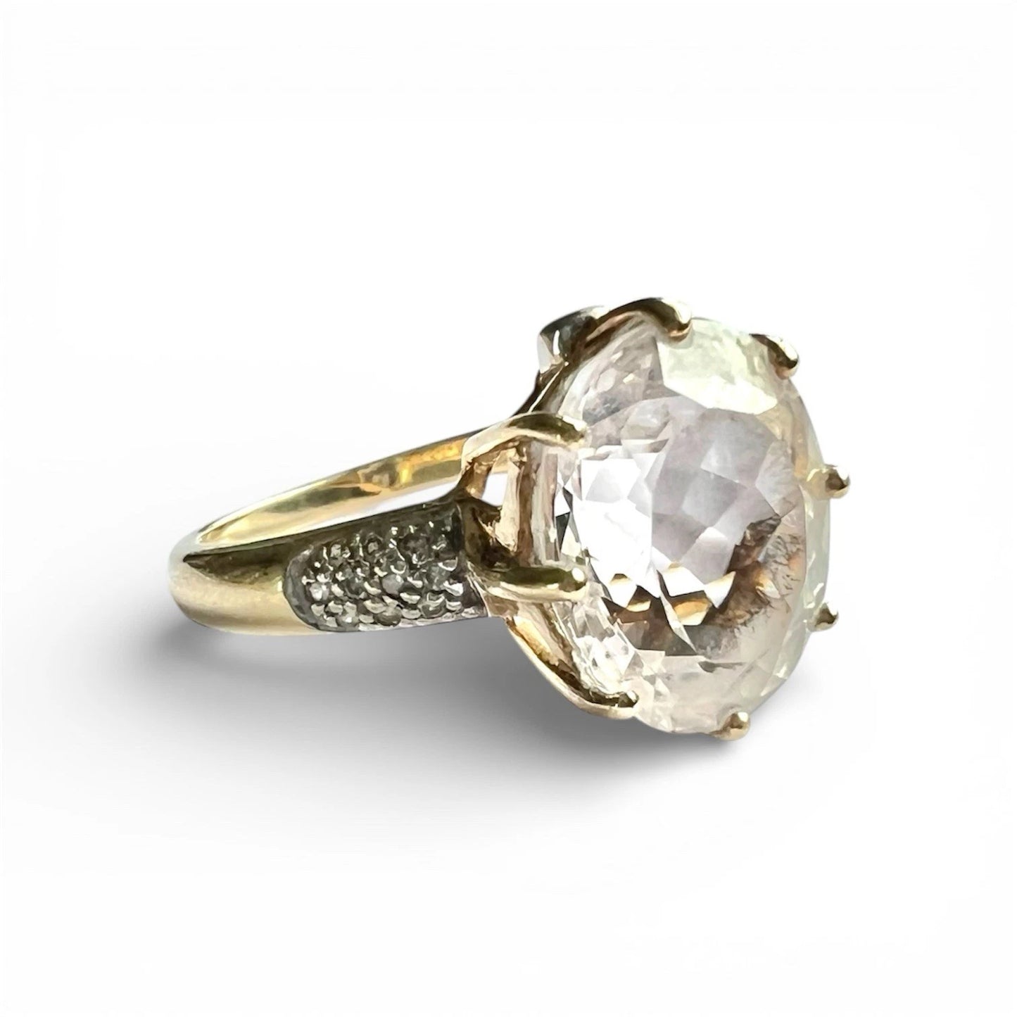 Gold ring with a large clear quartz gemstone on a white background close up side view 