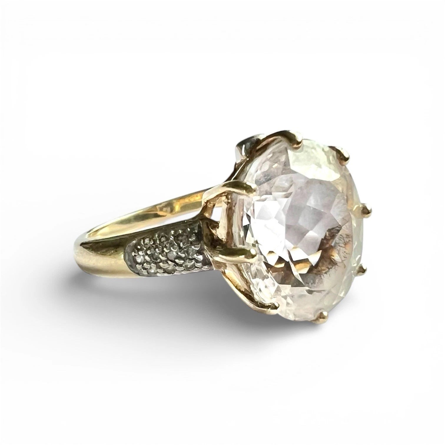 Gold ring with a large clear quartz gemstone on a white background close up side view 