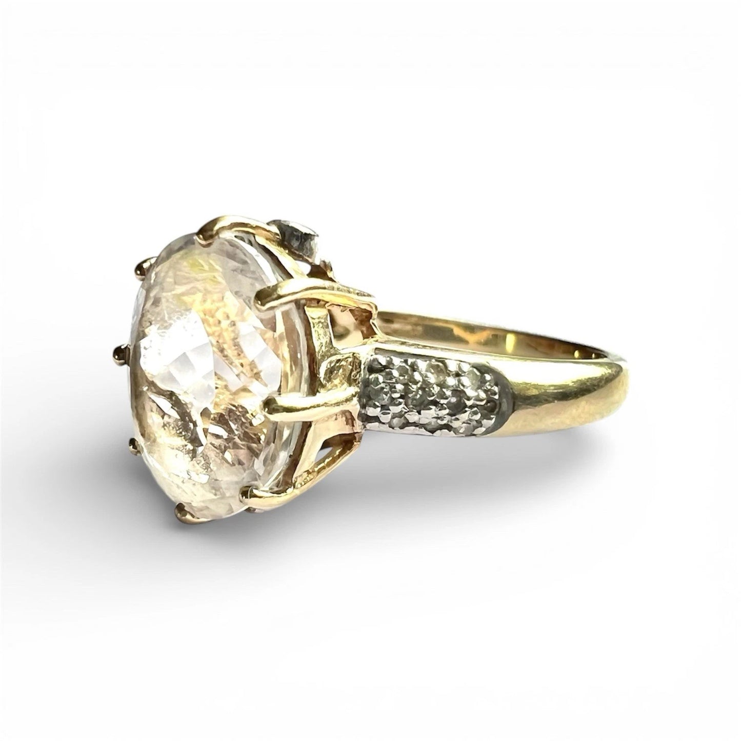 Gold ring with a large clear quartz and diamond on a white background