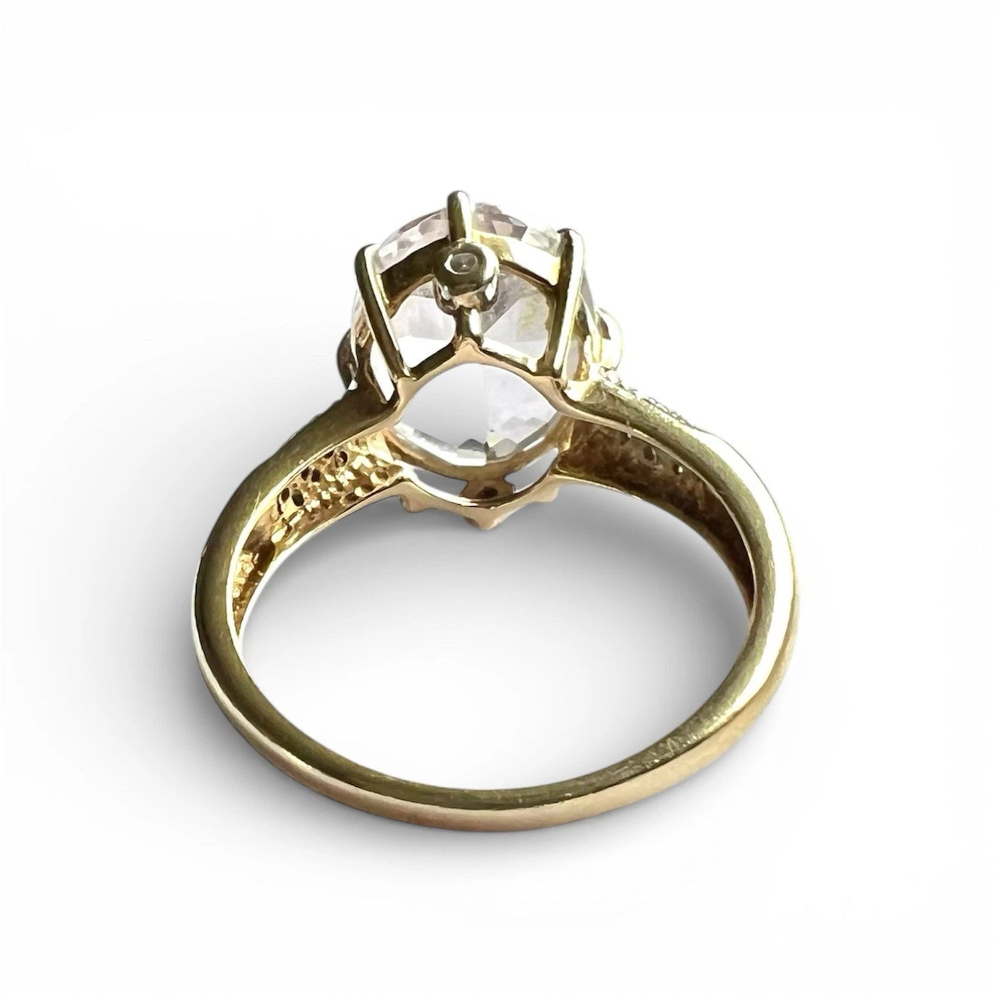 Gold ring with a clear quartz and diamond gemstone on a white background rear view close up of setting and gold band 