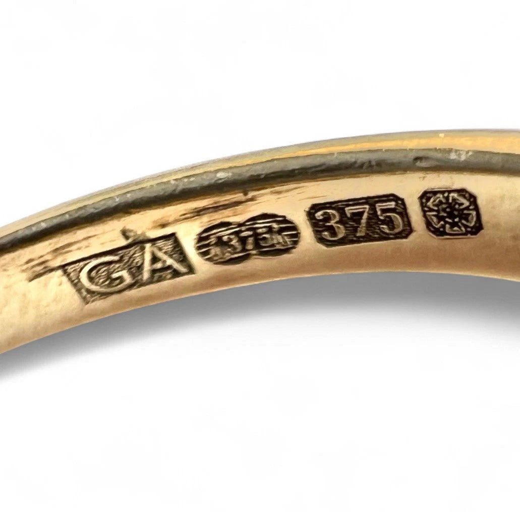 Gold ring with visible hallmarking on a white background