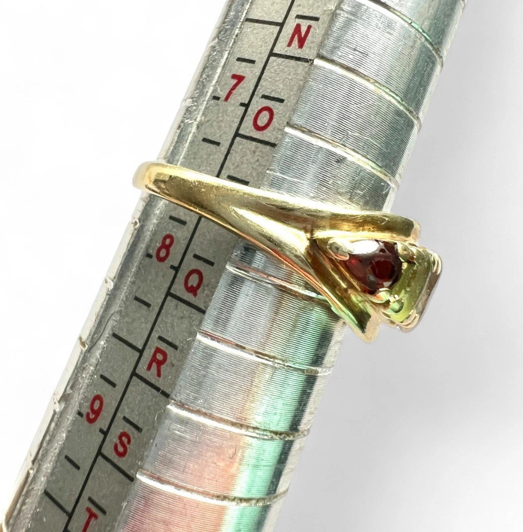 Gold ring with multicoloured gemstone on a metal ruler