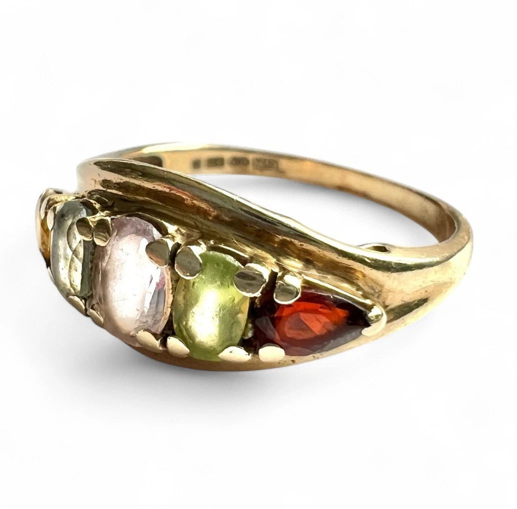 Gold ring with five multicoloured gemstones on a white background close-up view 