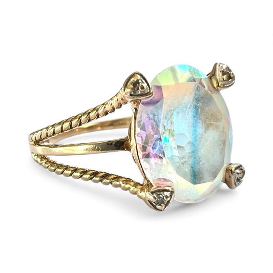 Gold ring with a colourful mystic quartz gemstone and rope style band on a white background close up 