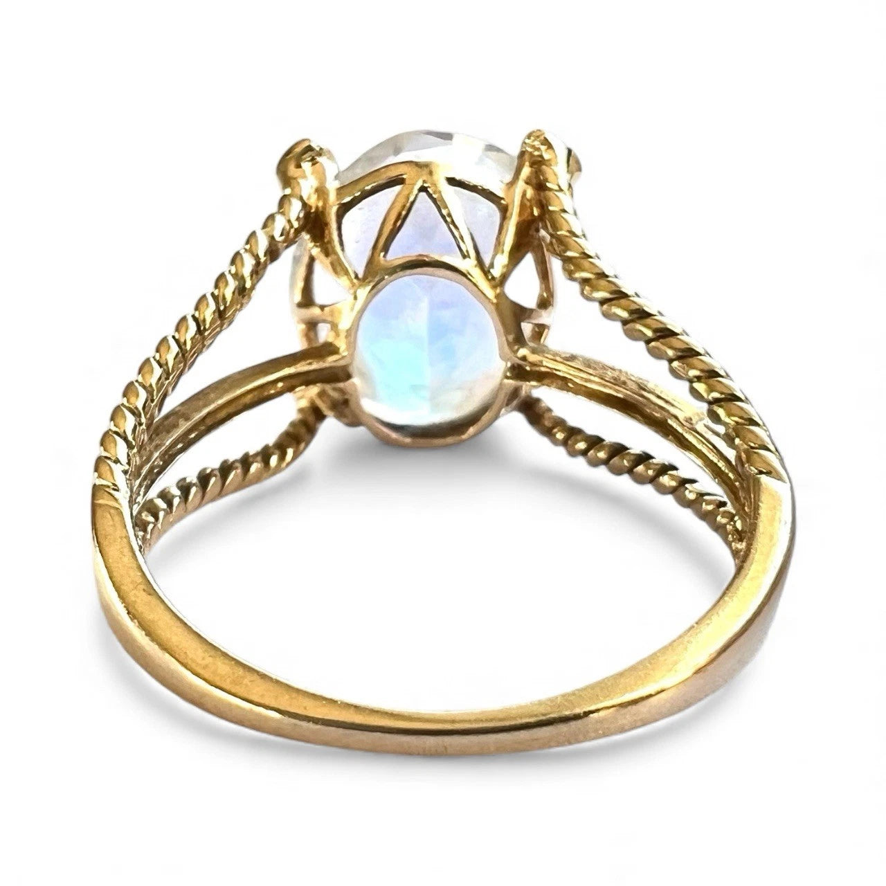 Close-up rear view of gold ring with a central mystic quartz gemstone on a white background