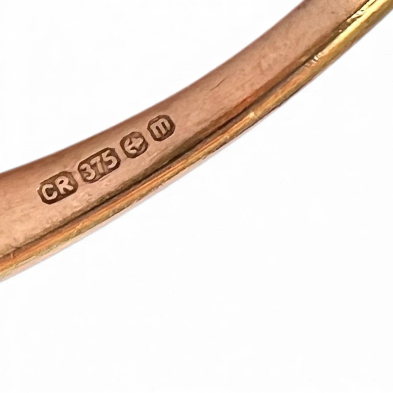 Close-up of a gold ring with visible hallmarks on a white background