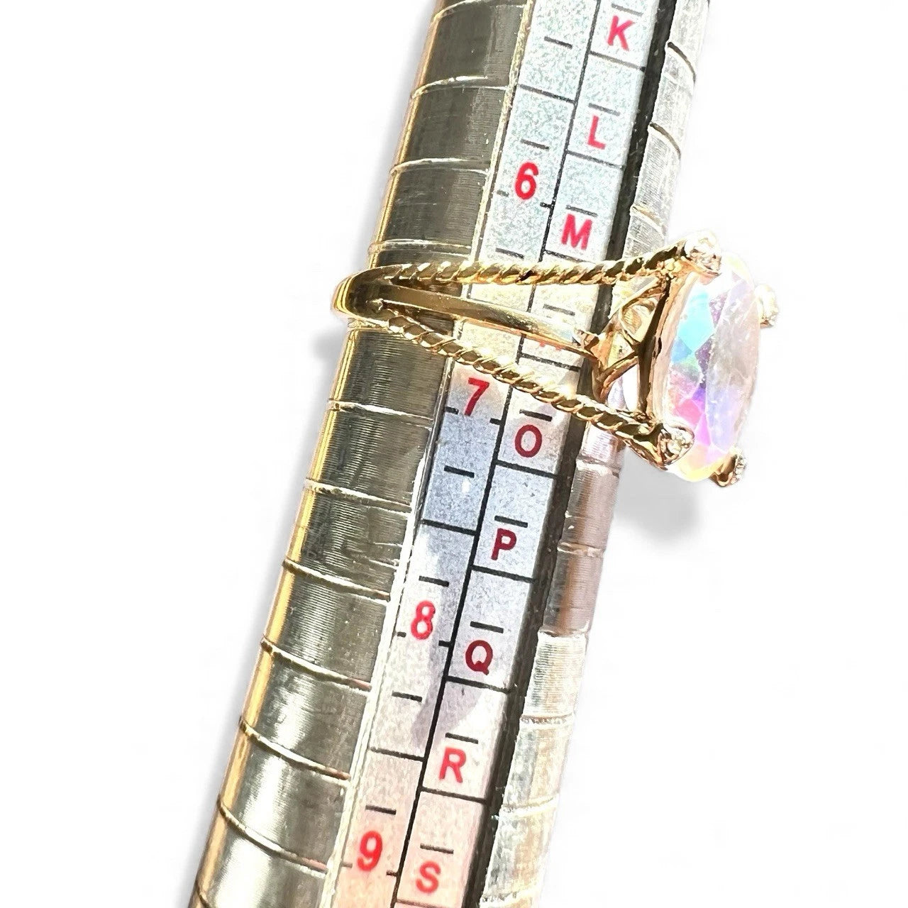 Gold ring with a colourful mystic quartz gemstone on a ruler for size reference