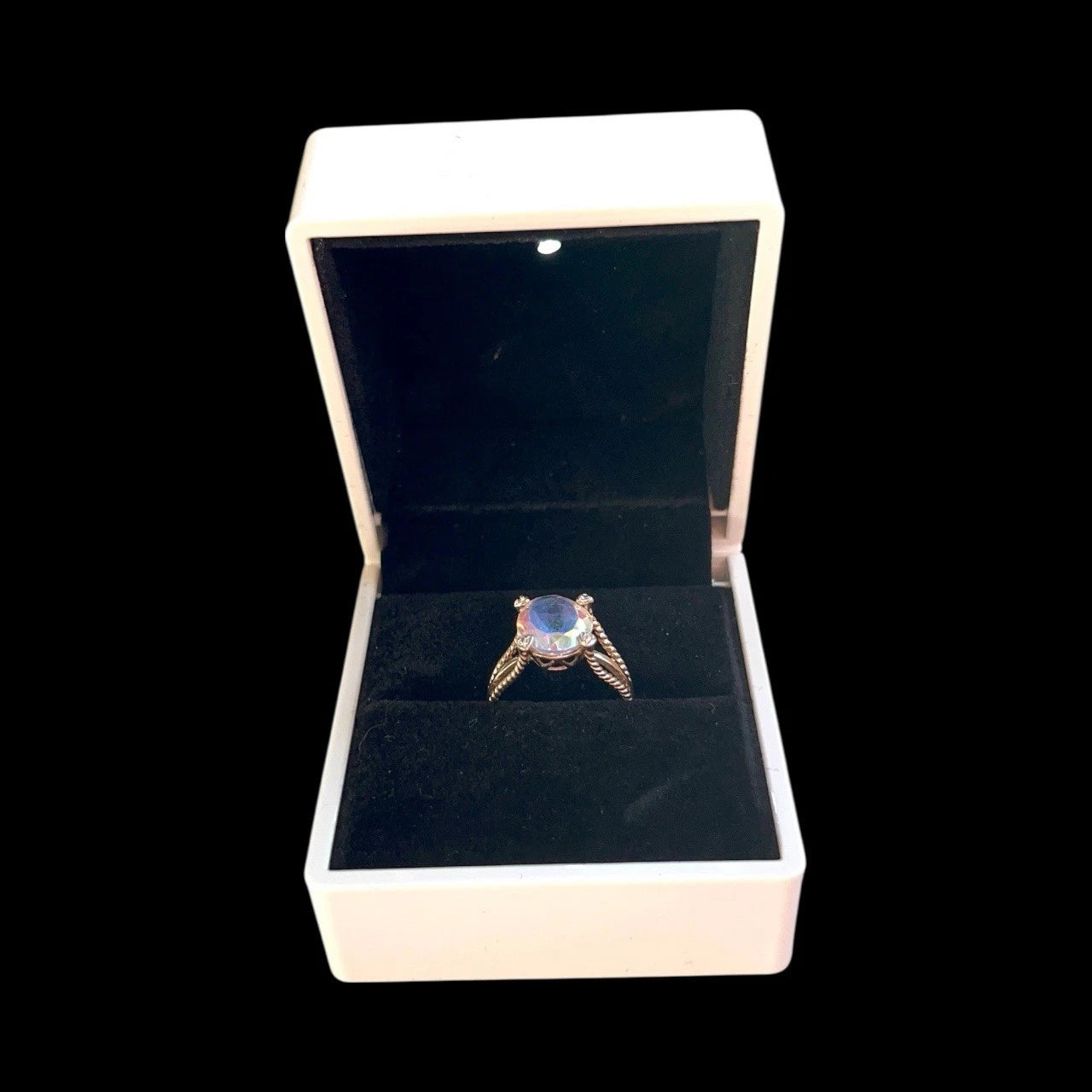 Ring with a mystic quartz gemstone in an open jewellery box on a black background