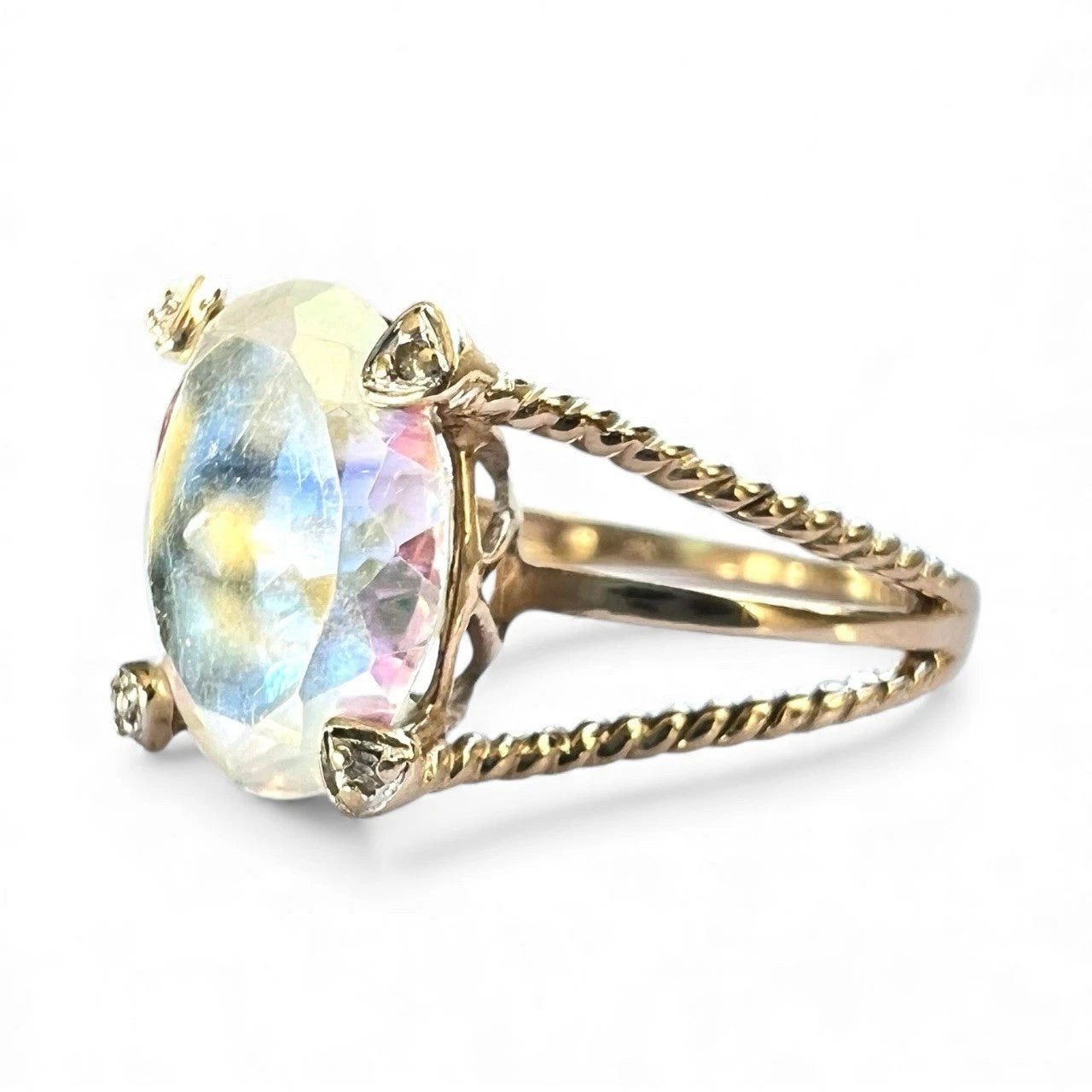 Gold ring with a large colourful mystic quartz gemstone with rope style band on a white background, close-up side view 