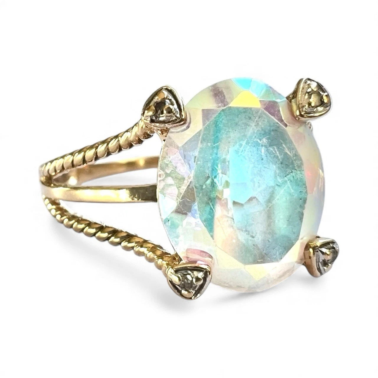 Close-up gold ring with a large, colourful mystic quartz gemstone and rope twist band on a white background