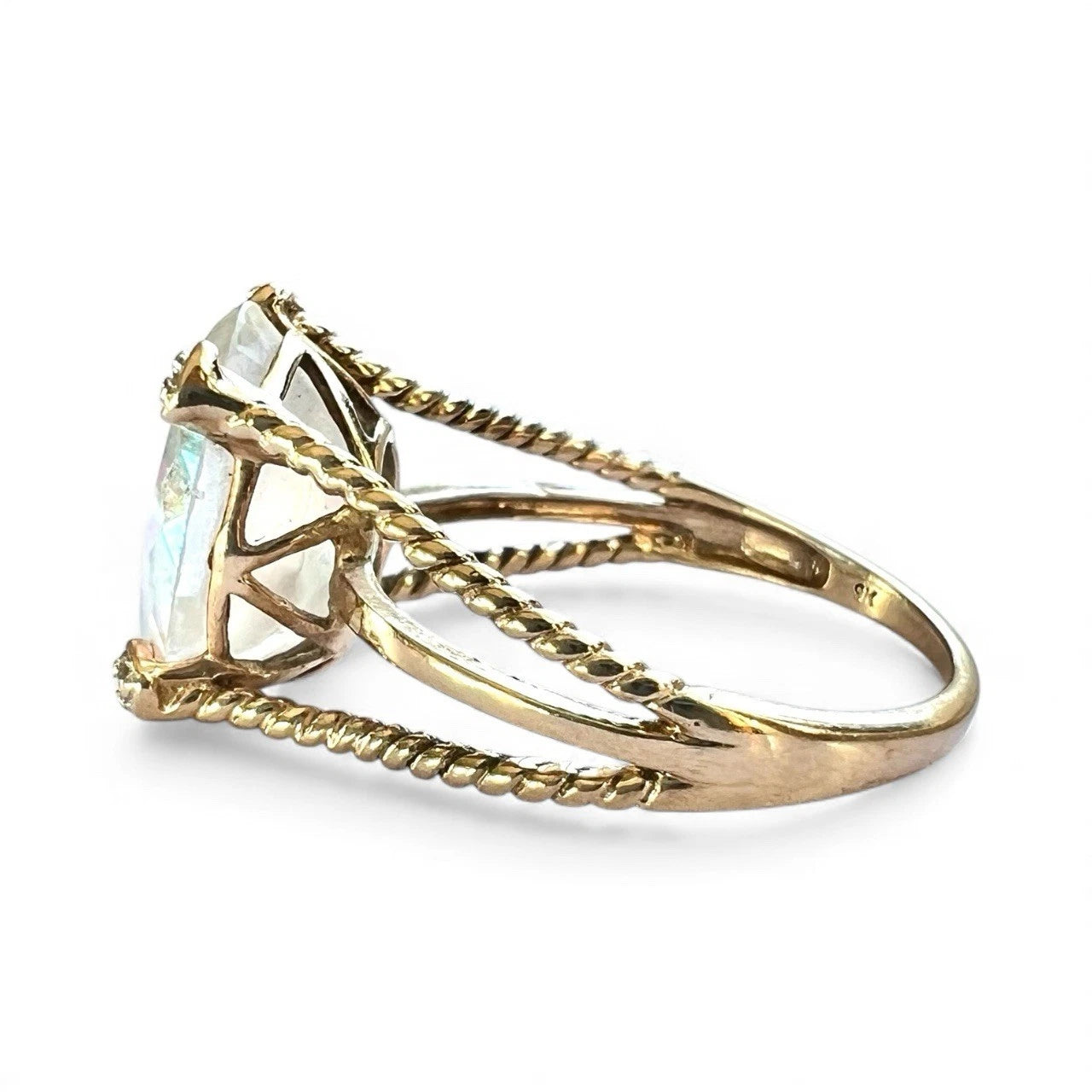 Gold ring with a large mystic quartz gemstone and rope twist design band on a white background, close-up side view 
