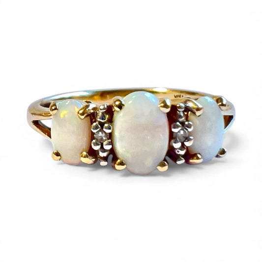 Gold ring with three opal stones on a white background