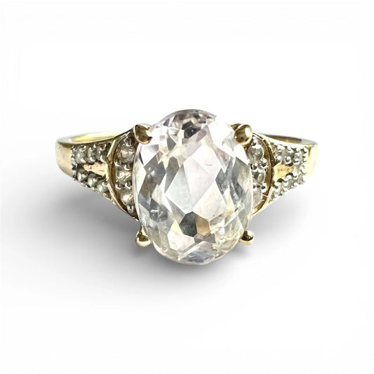 Gold ring with a large central quartz gemstone and diamonds on a white background
