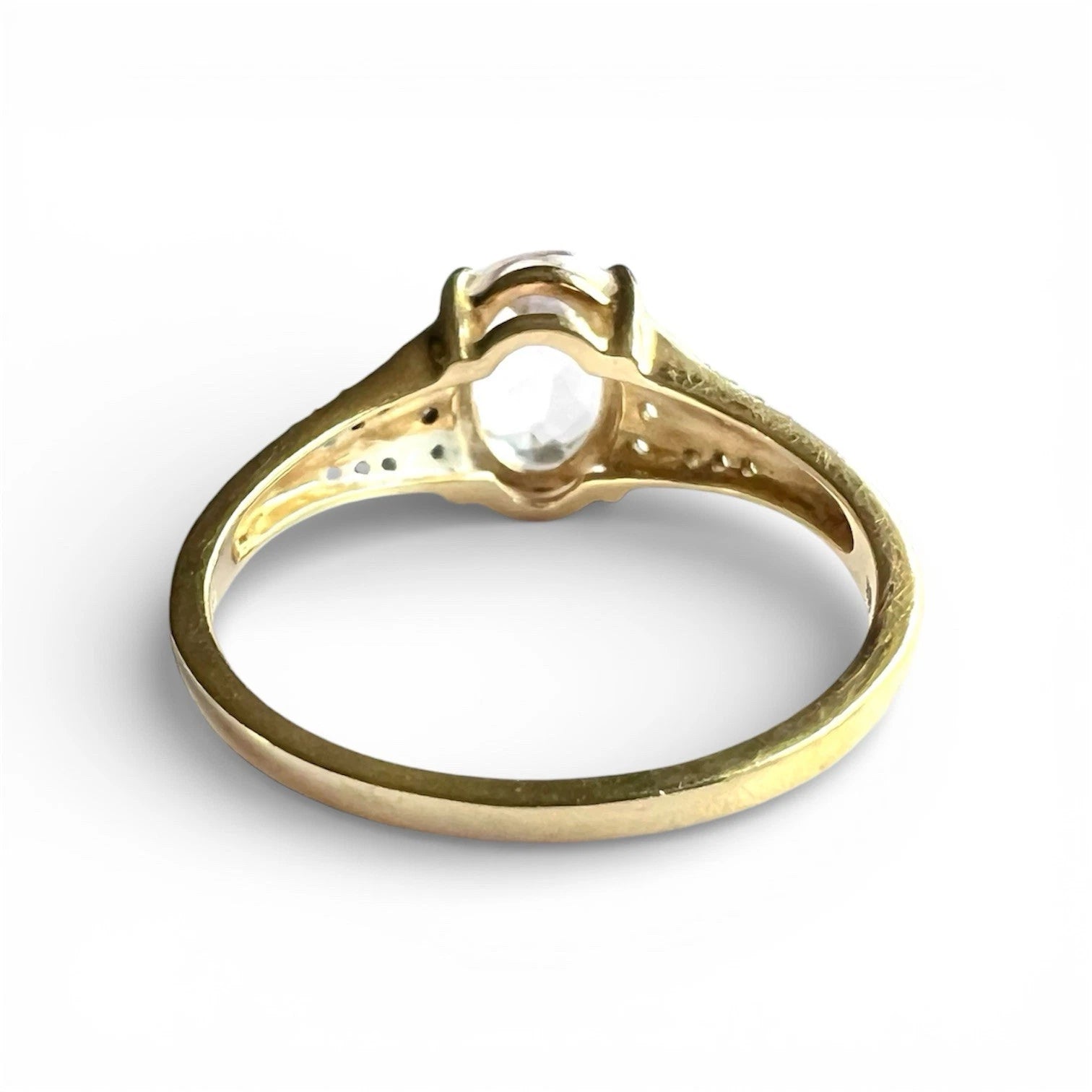 Gold ring with a central gemstone on a white background. Close up rear view of setting and gold band 