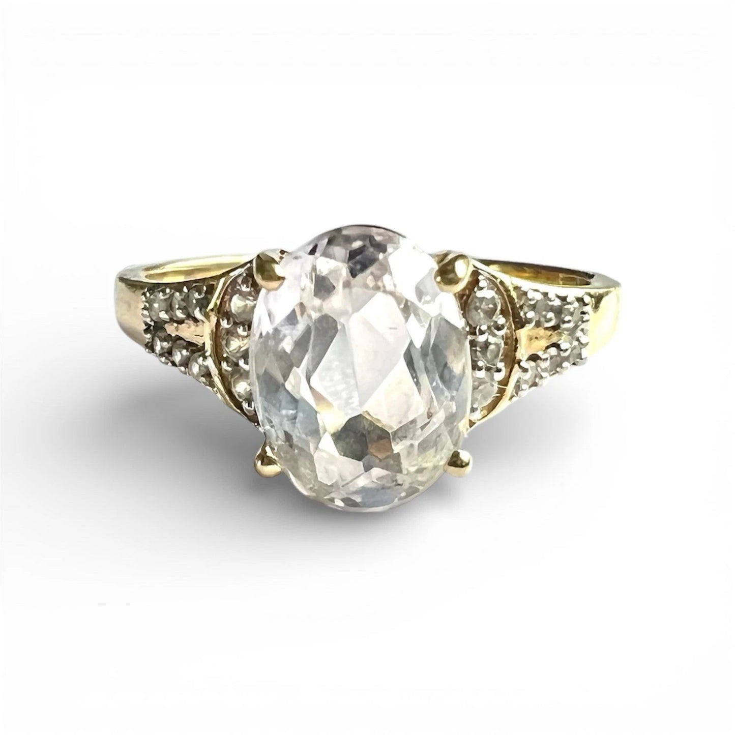 Gold ring with a large central gemstone and smaller diamonds on a white background. Close up front view 