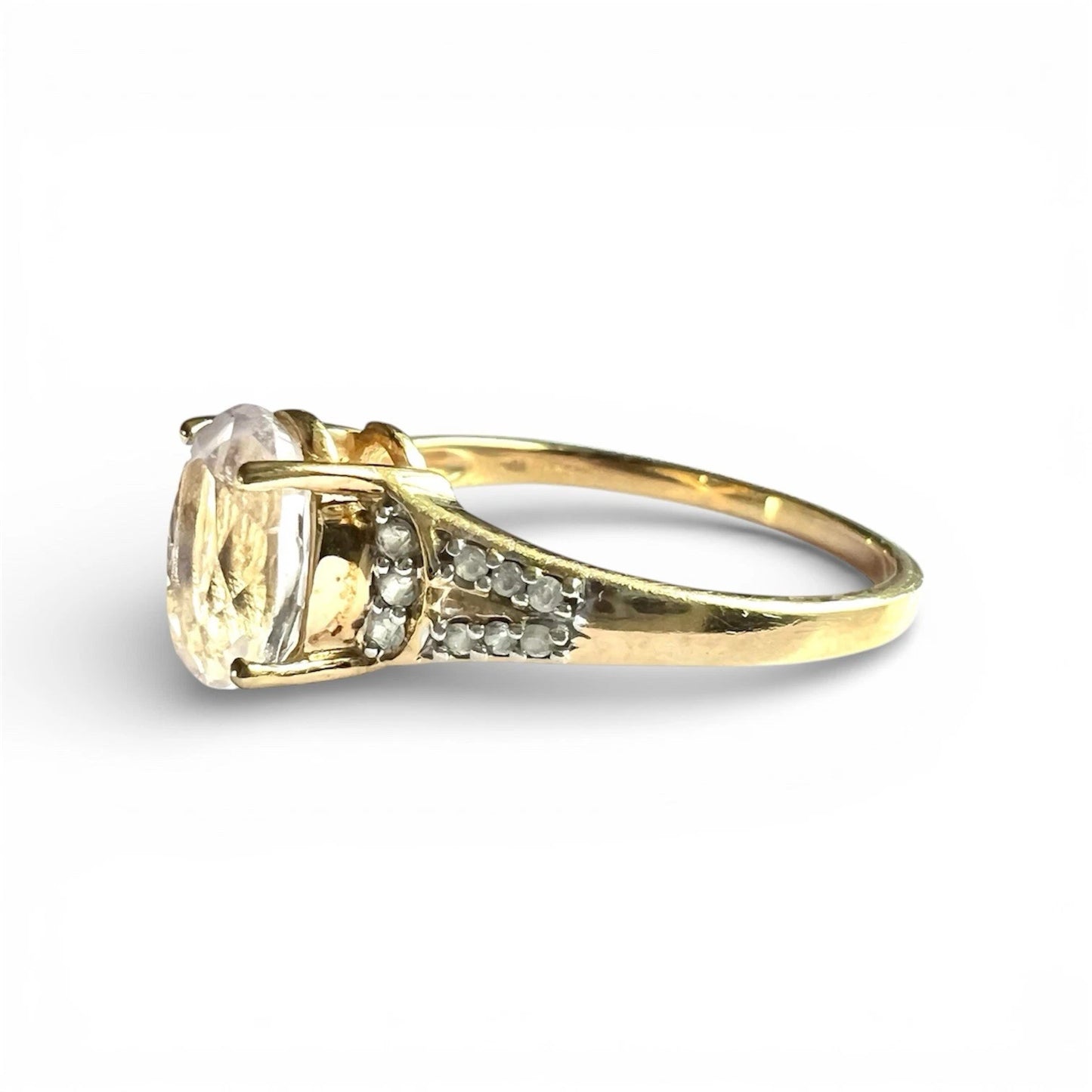 Gold ring with a large quart gemstone and diamonds on a white background. Close up side view 