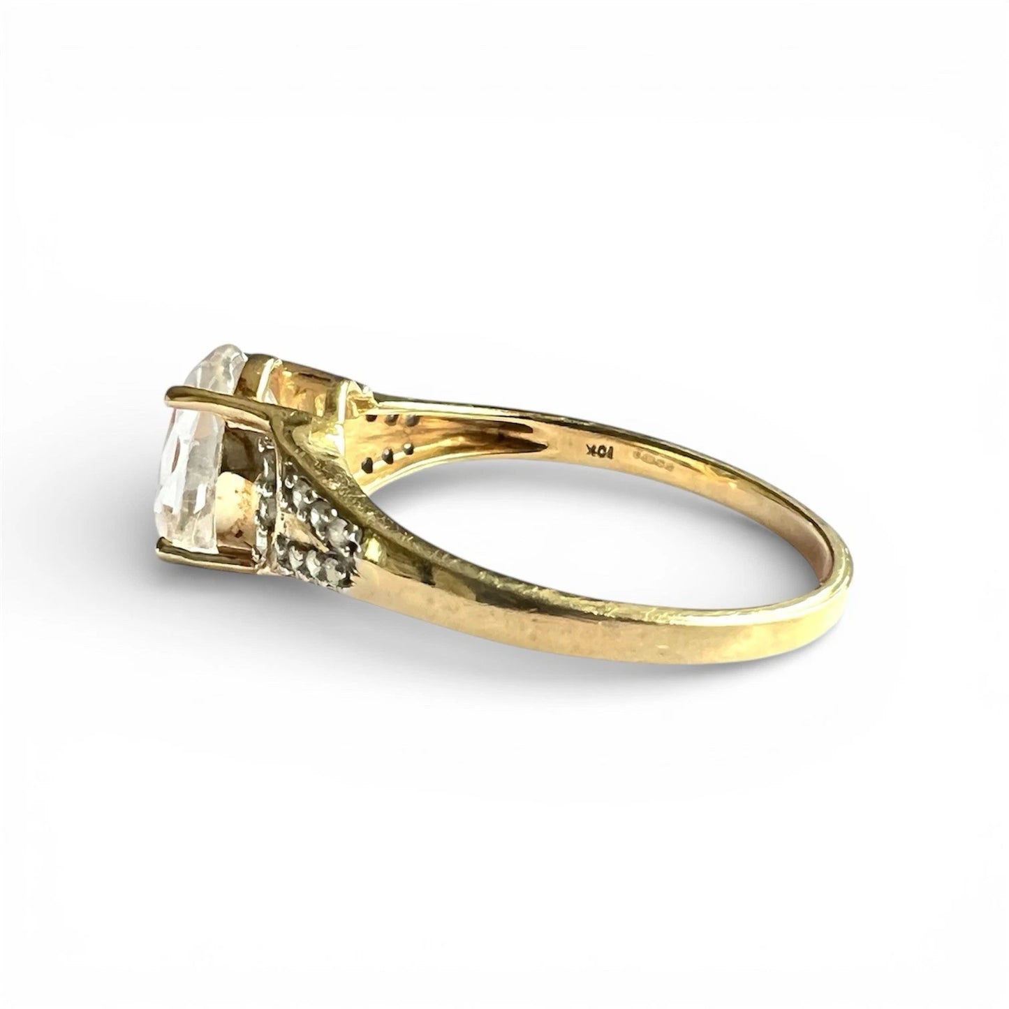 Gold ring with a clear gemstone on a white background. Close up side view 