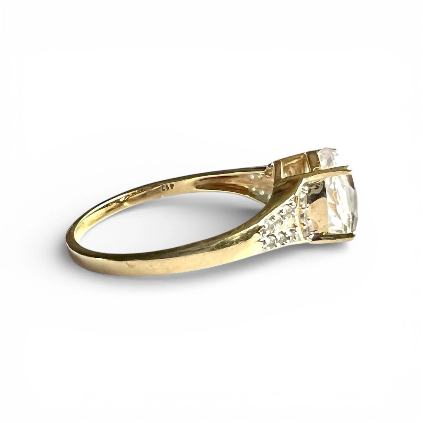 Gold ring with a quartz gemstone and diamonds on a white background. Close up side view 