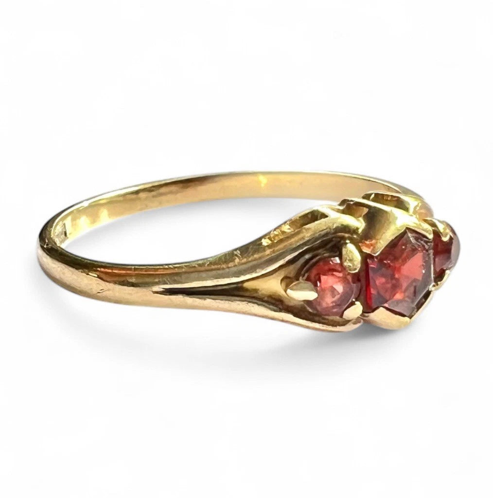 Gold ring with red gemstones on a white background
