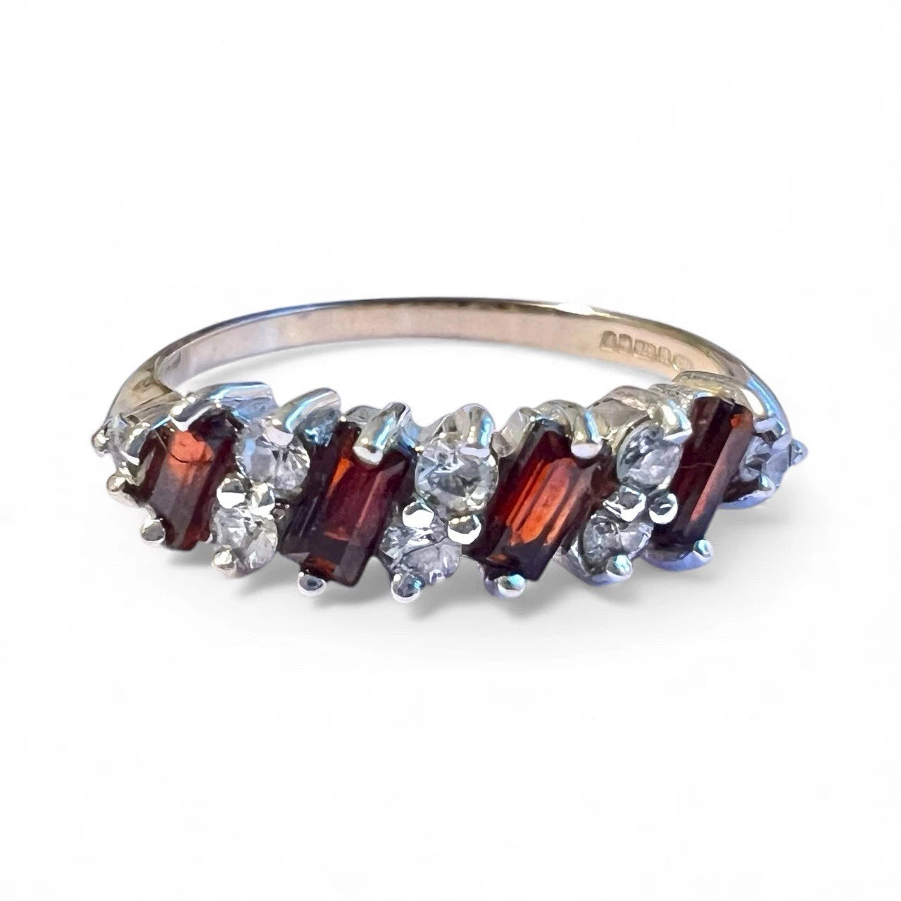 Gold ring with red and clear gemstones on a white background