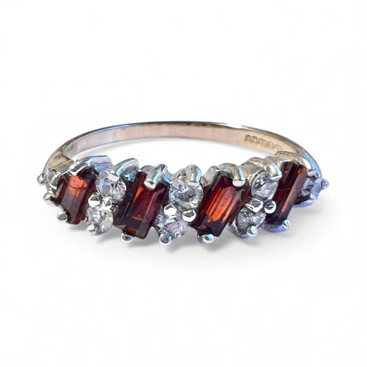 Gold ring with red and clear gemstones on a white background